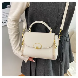 Gros plan du sac en cuir crème avec boucle dorée en M et détails de fermeture éclair