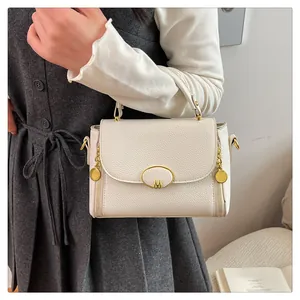 Détail d'un sac à main blanc en cuir grainé avec boucle logo M et finitions dorées