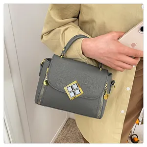 Détail du sac à main gris avec cuir grainé litchi et boucle dorée élégante de luxe