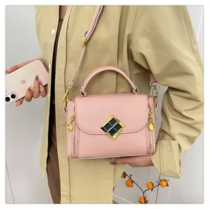 Détail d'un sac rose avec texture litchi, boucle dorée et bandoulière réglable