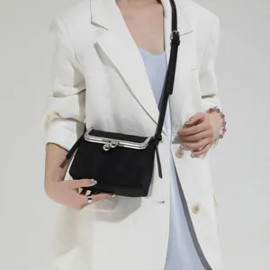 Sac coquille noir chic avec motif litchi et fermoir boule argenté sur un modèle en blanc