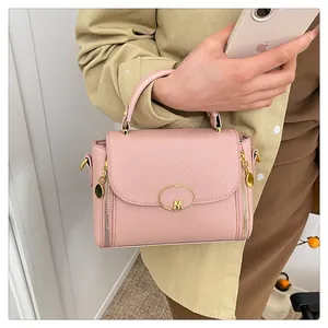Détail du sac à main rose texture litchi avec boucle M dorée et fermetures éclair