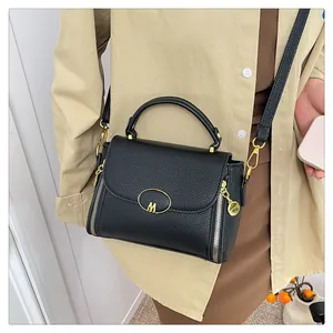 Détail du sac noir à grain de litchi avec logo M doré et zips décoratifs