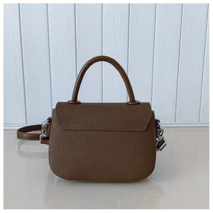Détail d'un sac à main en toile marron avec anses en cuir et boucles en métal argenté