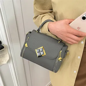 Sac à main gris foncé texture litchi avec fermoir doré et pendentif boule élégant