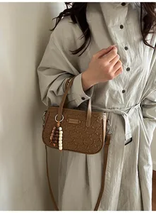 Vue détaillée du sac à main marron avec texture géométrique et breloques en perles