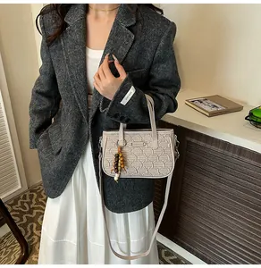 Détail du sac à main matelassé beige avec pompon en perles de bois et motifs texturés