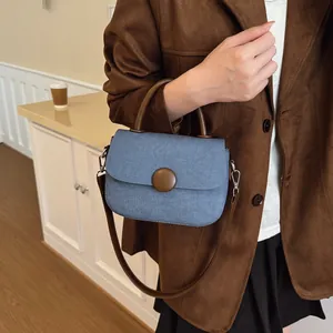 Sac à main en denim bleu clair avec poignée en cuir marron dans un décor quotidien