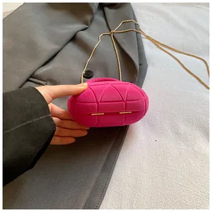 Detail of a magenta velvet pebble chain bag with geometric quilted pattern