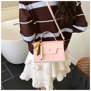 Detail of light pink crossbody bag featuring chic colorful beaded pendant and clasp