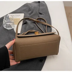Detail showing the brown litchi grain leather texture and gold twist lock of the shoulder bag
