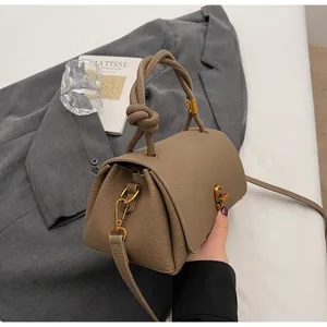 Detail of lychee pattern leather handbag with knot handle and golden twist lock closure
