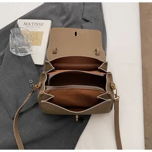 Detail view of khaki lychee leather shoulder bag with three inner compartments and gold zipper