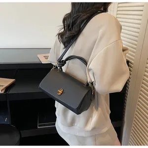 Close-up of black lychee grain leather handbag with gold twist lock and knotted top handle