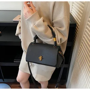 Detail of black lychee grain leather handbag with gold buckle and adjustable strap