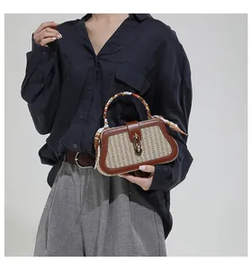 Detail of woven straw handbag with brown leather trim and silk scarf wrapped handle