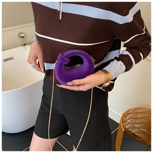 Close-up of a purple velvet knotted mini bag with gold chain strap on a fashion model