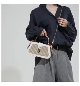 Detail of woven straw handbag with white leather trim and silk scarf wrapped handle