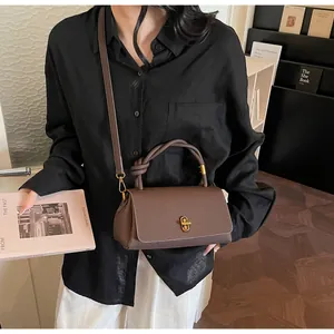 Detail of brown lychee grain leather handbag featuring a creative knotted handle and gold lock