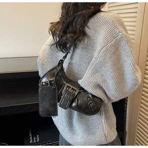 Detail of vintage black leather motorcycle shoulder bag with large metal buckle on sweater