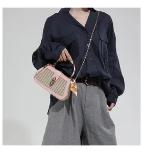 Detail of woven straw handbag with pink leather trim and scarf-wrapped handle