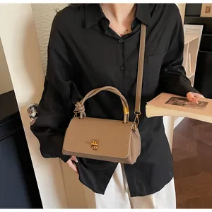 Detail of lychee pattern leather handbag with woven handle and gold twist lock clasp