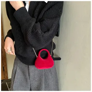 Close-up of bright red velvet mini handbag with geometric quilting and gold chain strap
