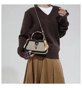 Detail of woven straw handbag with gold hardware, leather trim and silk scarf handle