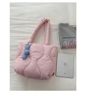 Pink quilted tote bag with blue checkered bow, shown next to a gray sweater and iPad