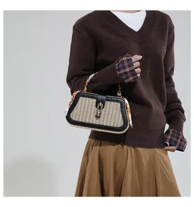 Detail of straw woven handbag with black leather trim and decorative scarf handle