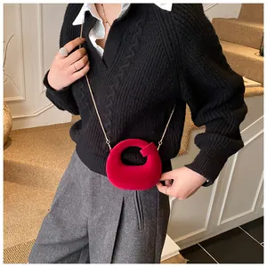 Close-up of rose red suede mini chain bag with elegant gold strap and hollow handle