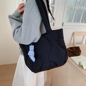 Black quilted puffer tote bag with wave stitching and blue plaid charm on shoulder