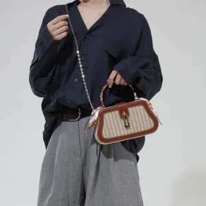 Straw woven crossbody bag with leather trim and silk scarf handle decoration on model