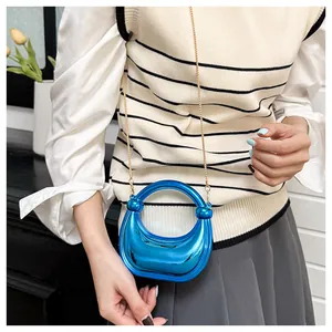 Gros plan du sac croissant bleu brillant à effet miroir avec bandoulière dorée