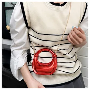 Mannequin portant un sac demi-lune rouge brillant avec une fine chaîne dorée