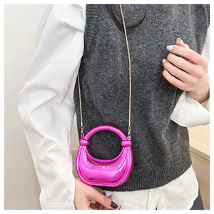 Sac demi-lune rose métallique avec fine bandoulière chaîne dorée porté par un mannequin