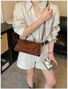 Brown gloss patent leather satchel bag with vintage retro style in indoor setting