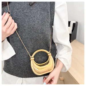 Sac demi-lune doré avec poignée ronde et bandoulière chaîne porté par un mannequin