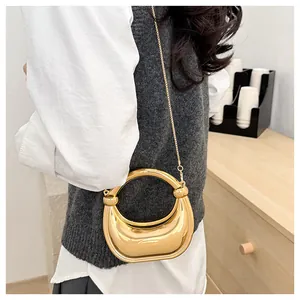 Détail du sac croissant doré poli avec poignée ronde et bandoulière en chaîne dorée
