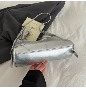 Détail du sac argenté à chaîne avec texture métallique froissée et bandoulière