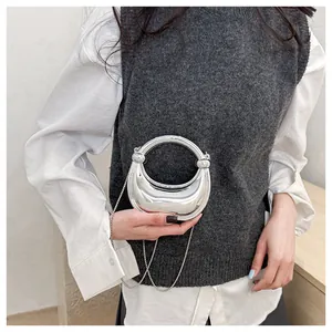 Détail du sac croissant argenté avec finition miroir métallique et bandoulière perlée
