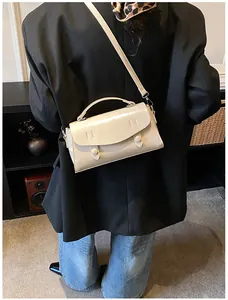 Back view of a model wearing a glossy cream satchel bag with elegant double buckles