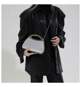 Close-up of sparkling silver sequins handbag with gold metal handle and chain strap