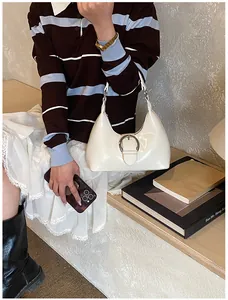 Détail du sac Hobo en cuir verni crème avec un grand ornement de boucle en métal argenté
