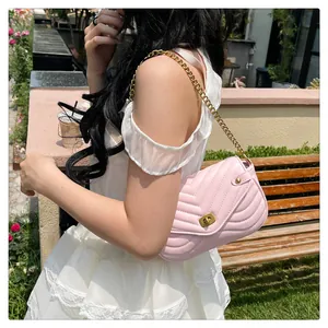 Detail of pink quilted shoulder bag with golden chain strap and vintage metal lock
