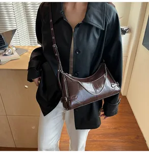 Détail du sac à bandoulière en cuir marron foncé avec texture craquelée et chaîne