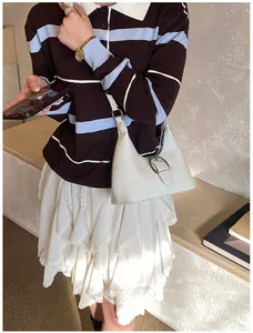 Détail d'un sac hobo blanc avec boucle argentée porté par un mannequin en intérieur chic