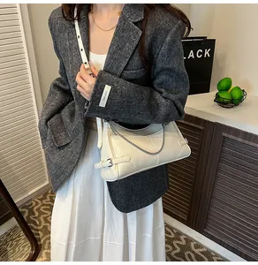 Sac sous le bras en cuir verni blanc crème avec chaîne argentée sur un modèle