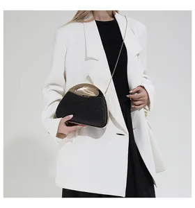 Detail of elegant black glitter evening clutch featuring a curved golden metal handle