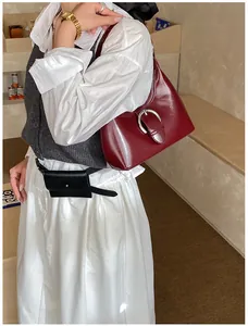Gros plan d'un sac à bandoulière bordeaux avec fini brillant et boucle en fer à cheval
